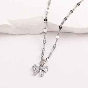 Gros plan du collier avec pendentif nœud argenté et zircons sur socle en pierre blanche