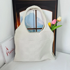 Detail of cream-white knitted tote bag with hollow weave texture and artistic Parisian style