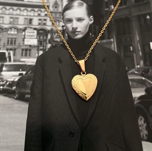 Golden heart locket necklace with vintage floral engraving on a stylish photo background