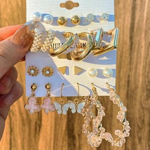 Detail of earring set with gold hoops, pearls, and pink butterfly charms on display card
