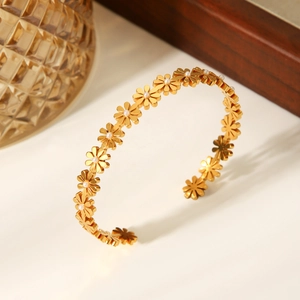 Macro detail of 18K gold stainless steel bracelet featuring daisy flowers and pearls