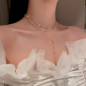 Detail view of a multi-layer gold Y-shaped necklace with pearls and rhinestones