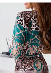 Detailaufnahme von Leopard- und Barockkettenmuster auf einem dunkelgrünen Langarmkleid