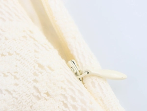 Détail en gros plan du tissu en dentelle blanc cassé avec une fermeture éclair invisible