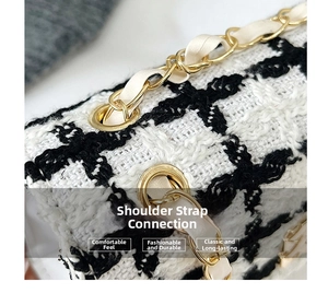 Detailed macro view of the metal chain strap and leather link on a black tweed bag