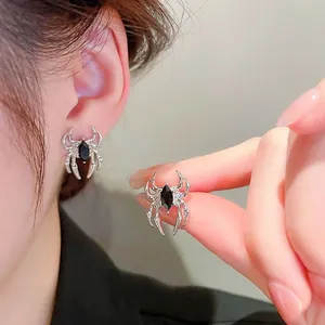 Detailed view of silver spider stud earrings with a black marquise gemstone center