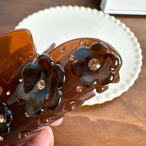 Elegant amber brown resin hair claw clip with diamond-encrusted flowers for women