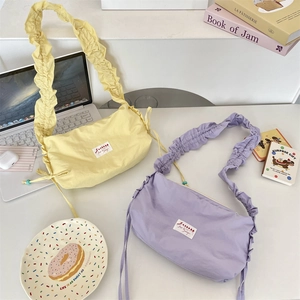 Close-up of stylish pleated canvas bags in soft yellow and purple with ruffle straps
