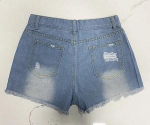 Flat lay back view of light blue denim shorts with distressed holes and frayed raw hem