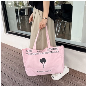 Pink canvas tote bag featuring black floral print and studio lettering detail