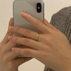 Close-up of minimalist gold bamboo knot ring worn on hand with mirror selfie context