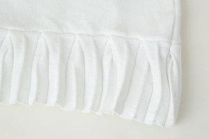 Gros plan sur la texture en tricot blanc et les détails de l'ourlet plissé