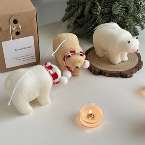 Macro detail of white polar bear candle with a red striped scarf in a cozy winter setting