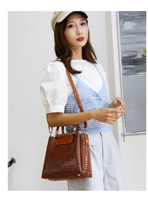 Close-up of caramel tote bag with woven texture and glossy finish worn by a model