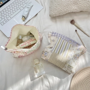 Flat lay of floral quilted makeup bags set with delicate wavy edges on white bedding