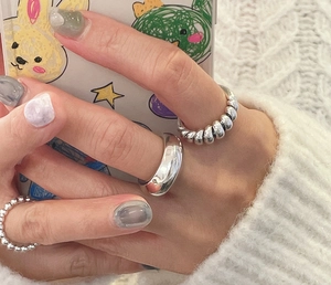 Close-up of 925 sterling silver ring set featuring knotted and spiral designs on hand