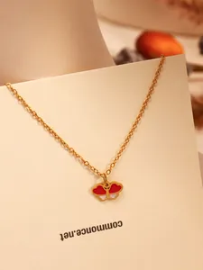 Vue détaillée d'un collier en acier inoxydable doré avec un pendentif papillon rouge et blanc