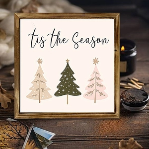 Close-up of a wooden square frame with 'tis the Season' text and stylized Christmas trees