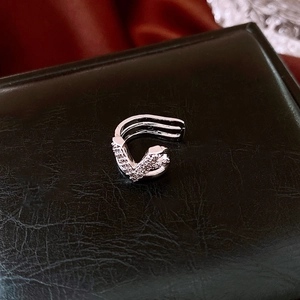 Detailed close-up of a silver-toned swan ear cuff with sparkling zircon inlay on black leather