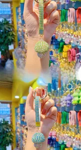Macro shot of green and blue crystal-encrusted mushroom keychains with gold metal rings
