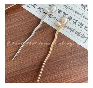 Detail of wave-shaped metal hairpins in gold and silver finish with elegant white pearls