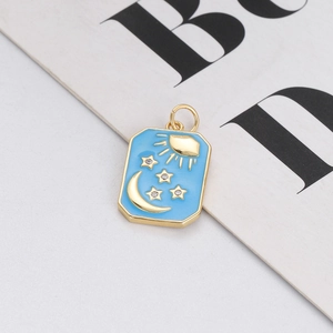 Detailed close-up of a rectangular gold sun and moon pendant with blue enamel and stars