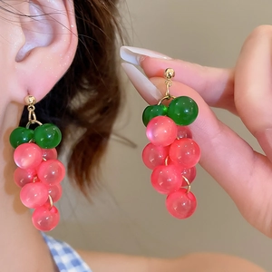 Detailed close-up of pink grape pendant earrings with gold studs and green leaf beads