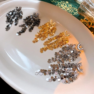 Detailed view of U-shaped sequin tassel earrings in gold, silver, and black metal colors