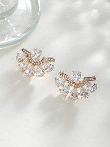 Macro shot of fan-shaped gold earrings featuring pear-cut zircon and crystal details