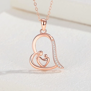 Close-up of rose gold heart pendant featuring a mother and child silhouette with zircons
