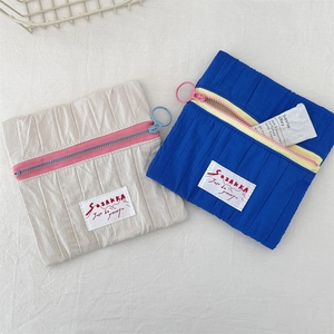 Detail of compact nylon makeup pouches with contrasting zippers and brand labels