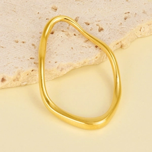 Detailed view of an irregular gold geometric pendant on a textured beige stone background