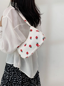 Detail of white nylon shoulder bag featuring vibrant red strawberry pattern prints