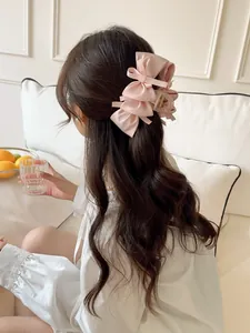 Detail of pink satin bow hair claw clip worn by model in a soft minimalist interior