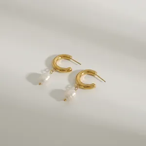 Detalle macro de pendientes de acero dorado con perlas barrocas sobre papel retro