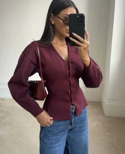 Détail d'un haut en tricot bordeaux avec col en V profond et texture de tissu côtelé fin