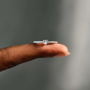 Macro shot of heart-shaped gemstone ring with white enamel and diamond pavé details