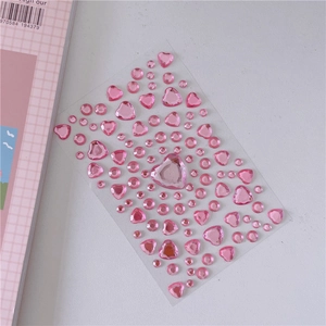 Close-up of pink heart and round acrylic gem stickers for DIY girl crafts