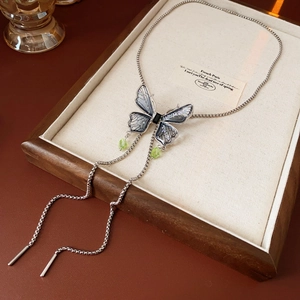 Detail of silver butterfly pendant with blue-purple gradient and green water-drop beads