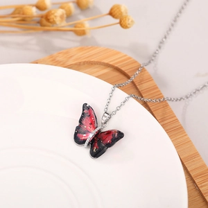 Macro view of gradient red and black butterfly pendant with golden glitter details