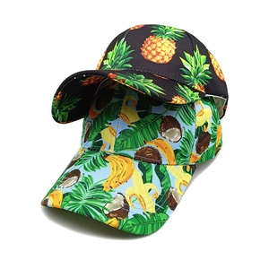 Detailed view of tropical fruit prints on canvas baseball caps with pineapple and banana patterns