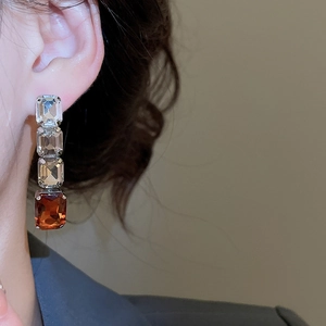 Close-up of elegant silver drop earrings with four square-cut multi-colored gemstones