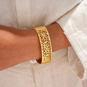 Detail of vintage gold hollow carved pattern on a stainless steel bangle bracelet
