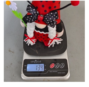 Detailed view of handmade ladybug gnome plush on a digital scale weighing 134 grams