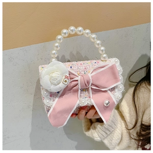 Detail showing pink tweed fabric with bow pearl handle and white camellia flower charm