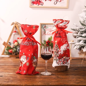 Christmas wine bottle bags with Santa and Reindeer prints on a cozy wooden table
