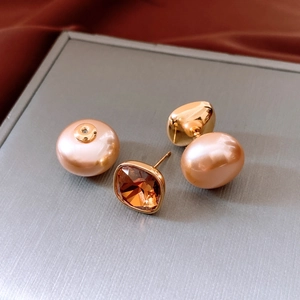 Detailed shot of amber crystal stud with large champagne pearl back on silk fabric