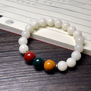 Detail of white Bodhi seed bracelet with cat claw charm and colorful beads on vintage book