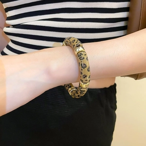Detailed close-up of an acrylic leopard print bamboo bracelet with gold metal spacer rings