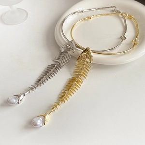 Close-up of gold and silver fishbone necklaces with small crystals and pearl details